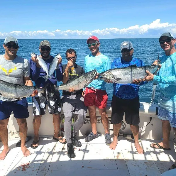 Six friends lined up on the stern, each holding a salmon