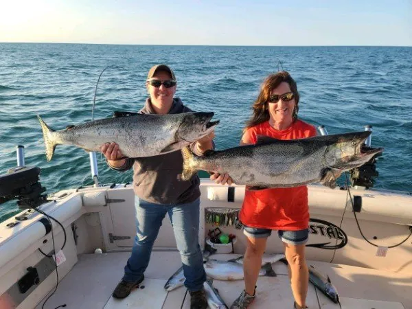 Couple holding two salmon on the stern
