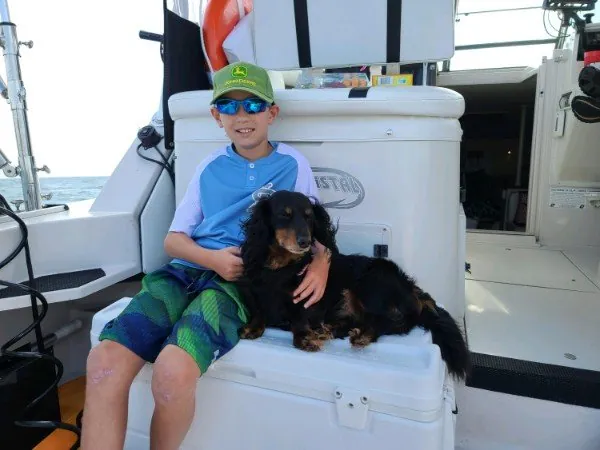 A boy and a dachshund sitting on the cooler